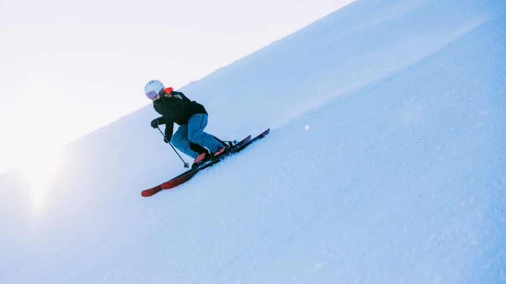 skier makes sweet turns on a low-lit flat and steep piste