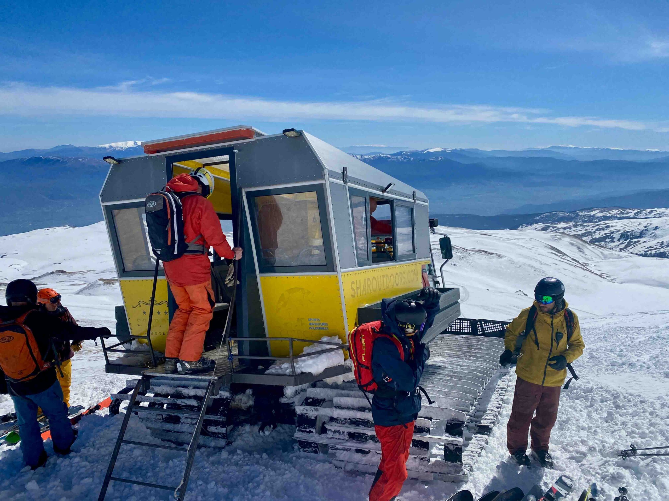 snowcat with skiers hanging around it