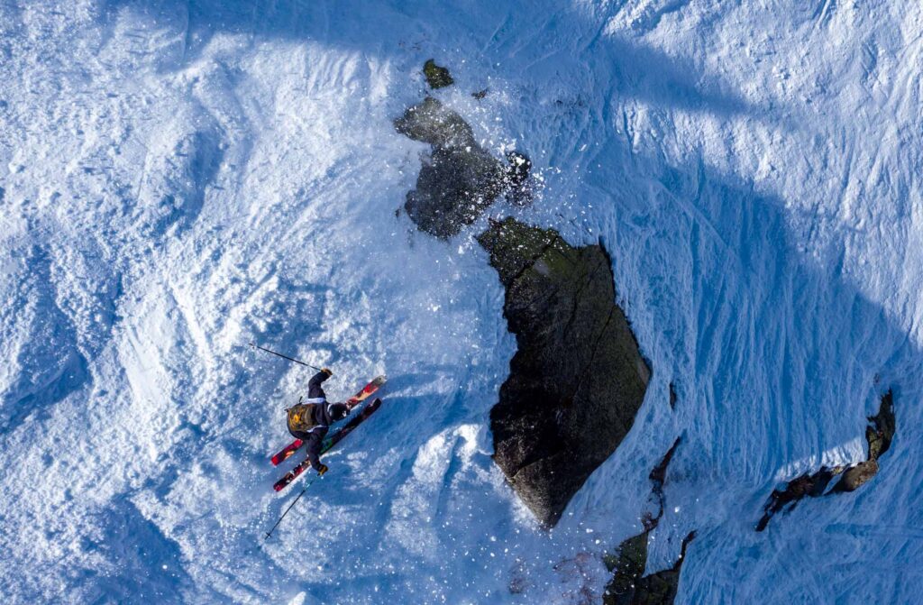 aerial shot of skier about to jump a rock
