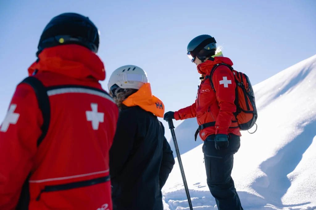 ski patrol and skier look out over mountains