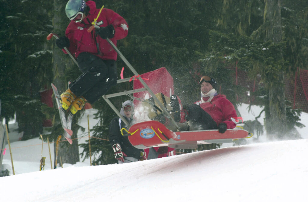 ski patrol pulls a blood wagon, taking some air off a roller