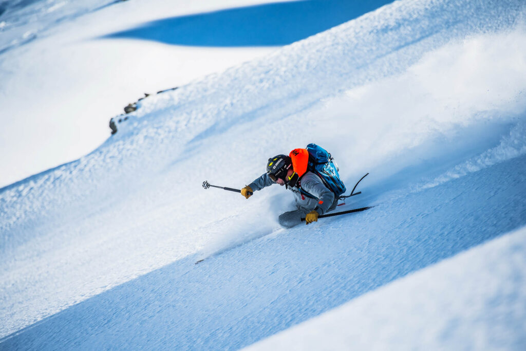 skier makes a beauty turn down fresh dry powder snow