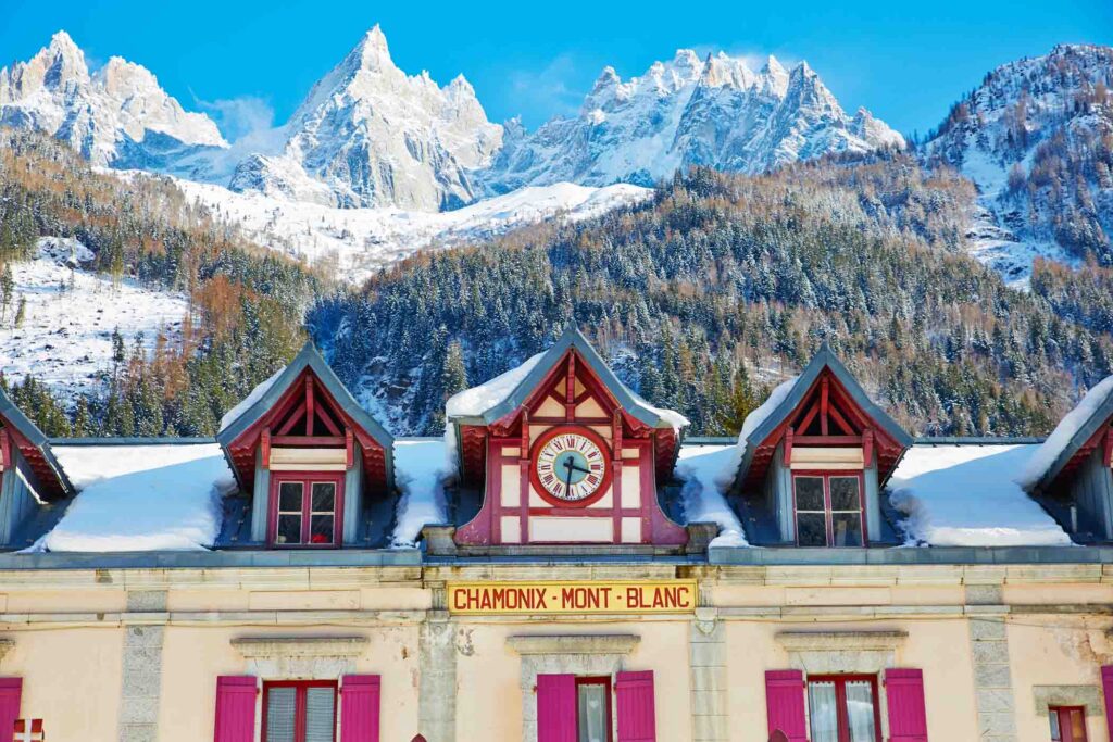 colourful Chamonix alpine train station roof against white peaks of the surrounding peaks, at the Winter Olympics centenary in Chamonix