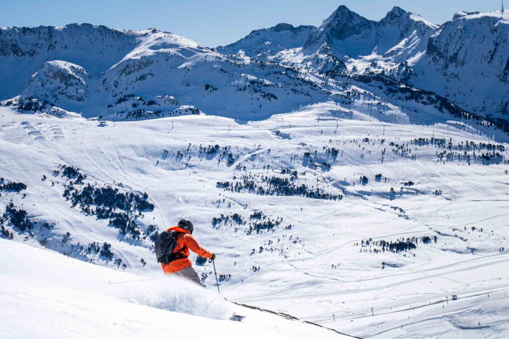 a skier in orange makes fresh tracks off-piste
