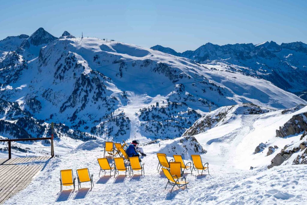 yellow deckchairs on a snowy mountain under the sun, with a great mountain view