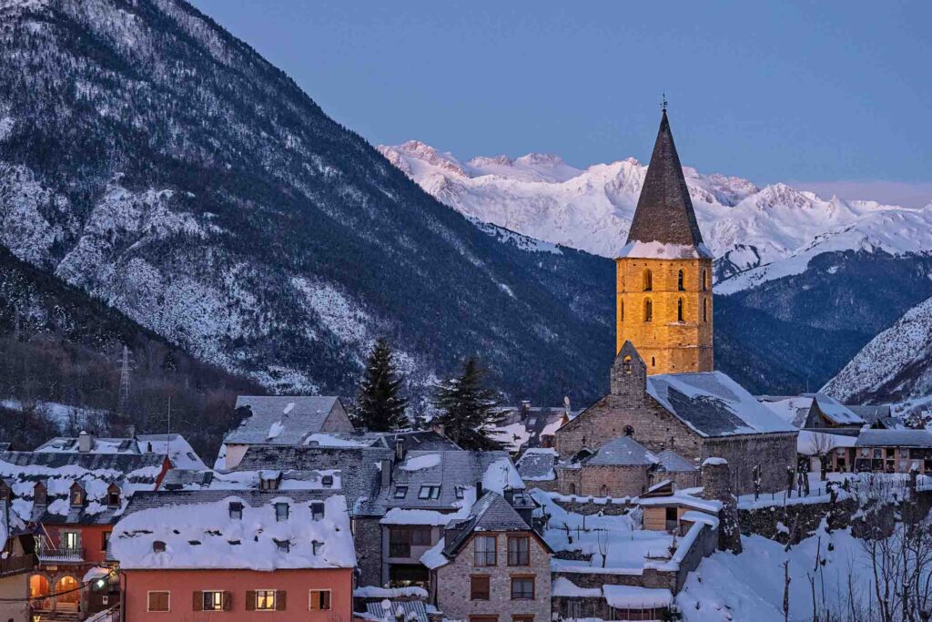 dusk over a snowy mountain village, a church tower catching last of the light