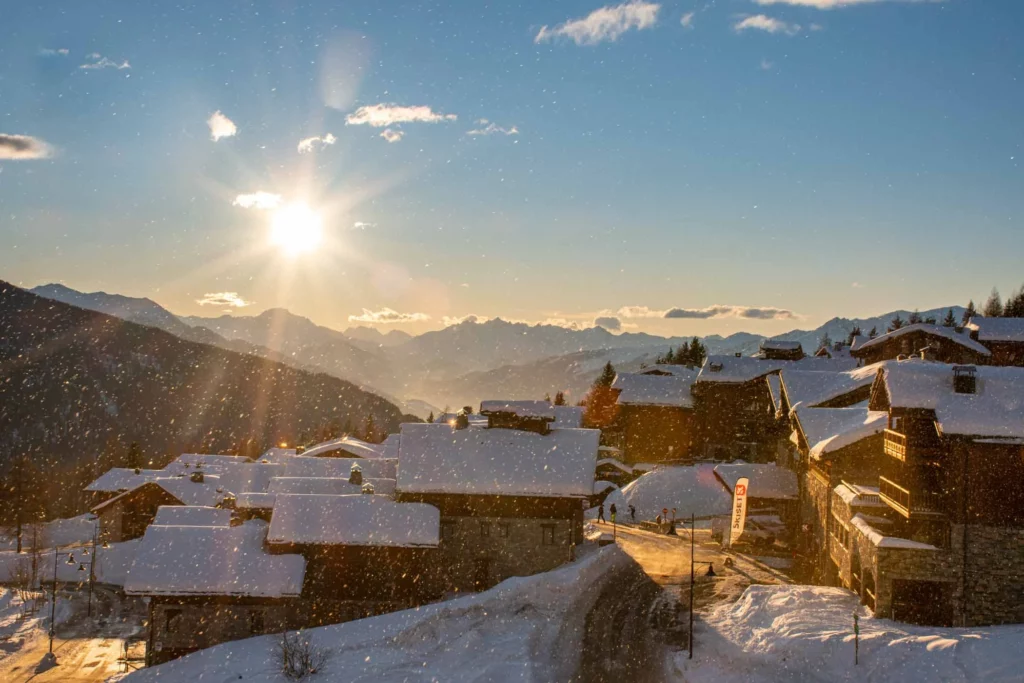 sunset (or perhaps sunrise) casts a golden glow over snowy roofs of a mountain village