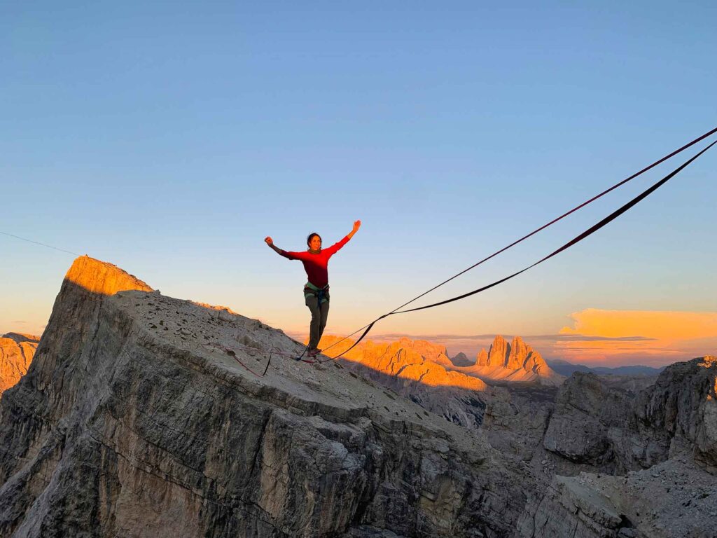 person highlining at top of Dolomite mountains at sunset
