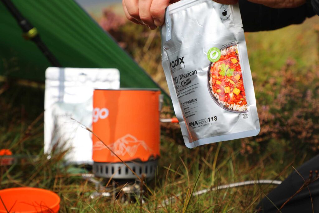 packet food and a camping water boiler set up on the grass